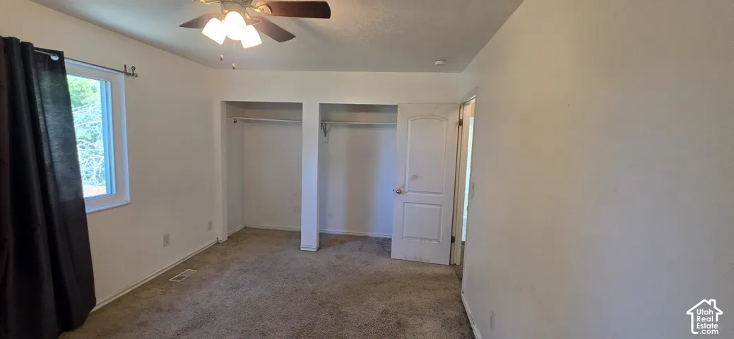 Room featuring neutral wall tones, wall-to-wall carpeting, dual built-in closets, and an overhead ceiling fan with integrated lighting