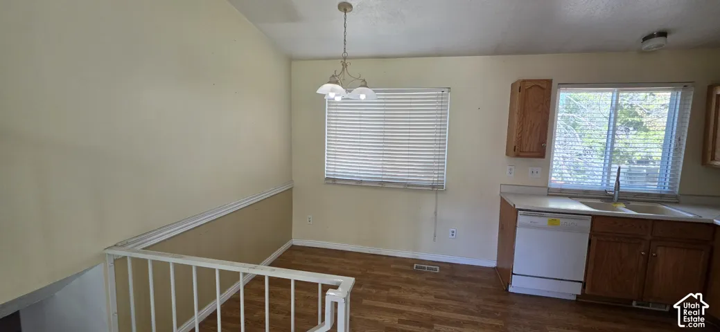 Wood-finish flooring, white metal railing, built-in wooden cabinetry, dual-basin sink, and a multi-light pendant fixture