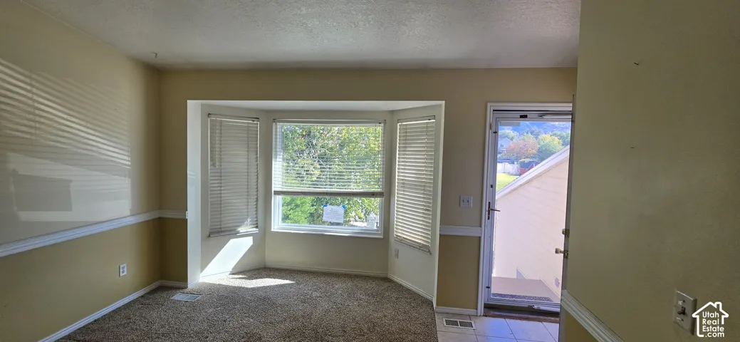 Bay window featuring horizontal blinds, chair rail molding, and exterior door with screen door