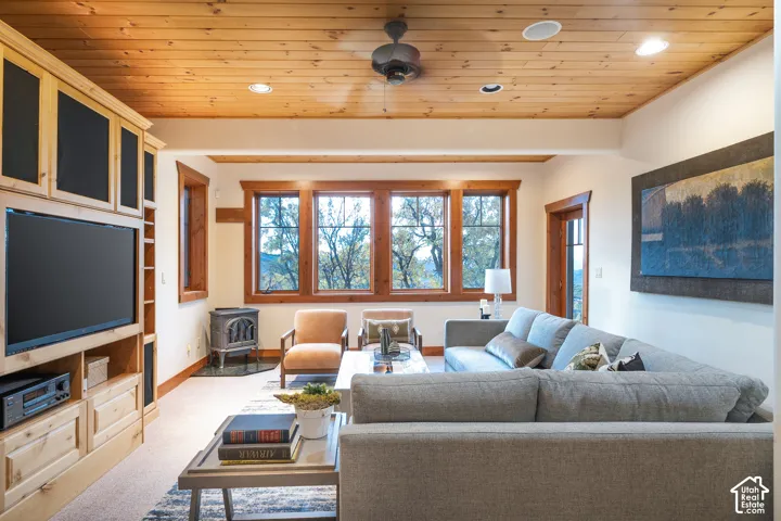 Wood-plank ceiling, built-in floor-to-ceiling cabinetry, cast-iron stove, and expansive windows with natural landscape backdrop