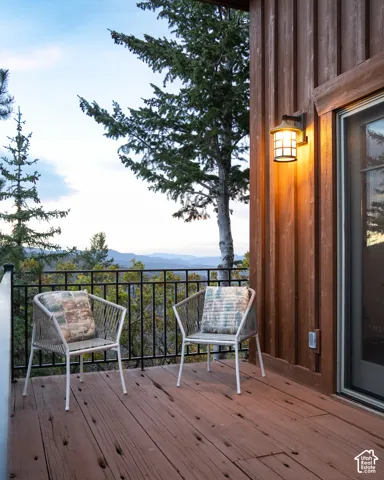 Exterior deck featuring wood-finish decking, vertical wood siding, a metal railing, and an attached wall-mounted lantern