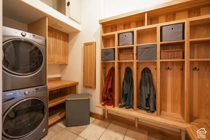 Custom floor-to-ceiling wooden locker system with integrated shelving and wall-mounted hooks, tiled flooring, wood cabinetry, and recessed upper storage
