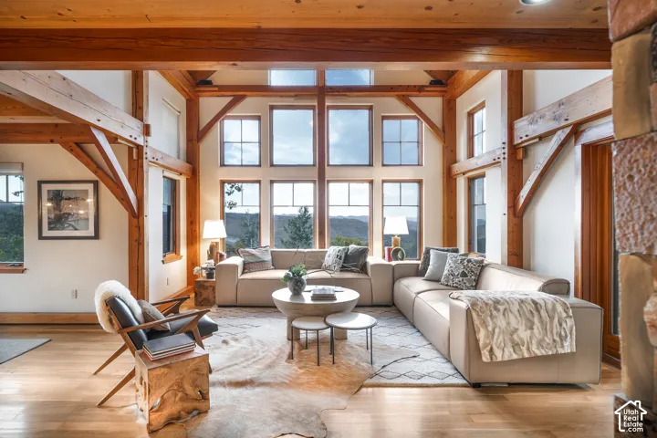 Exposed timber post-and-beam construction, double-height vaulted ceiling, expansive multi-pane windows, wood-finish flooring, and natural stone pillar element