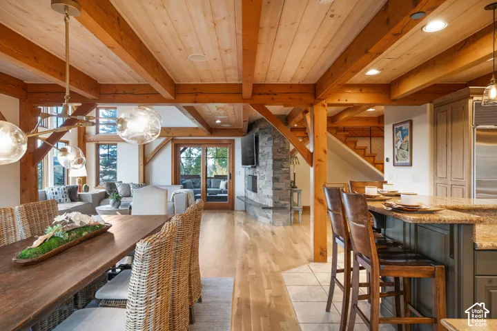 Exposed timber beams and tongue-and-groove wood ceiling, floor-to-ceiling natural stone fireplace, wood-finish flooring, and recessed lighting
