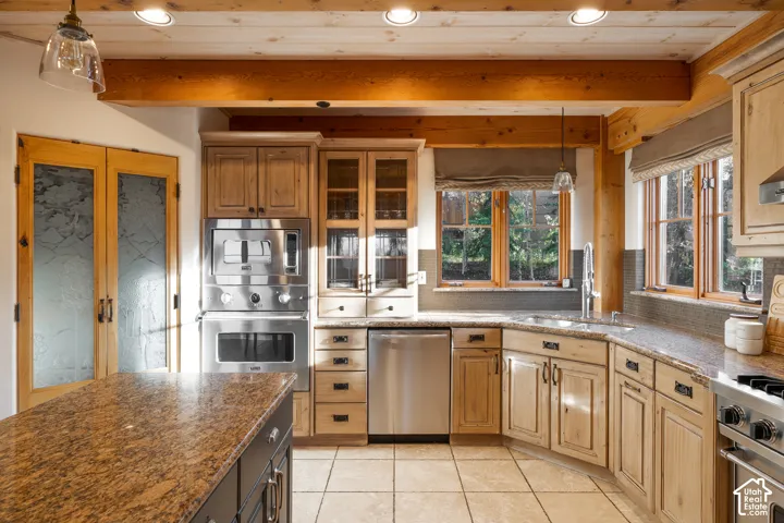 Kitchen featuring natural wood cabinetry, stone countertops, exposed timber ceiling beams, stainless steel appliances, and a center island