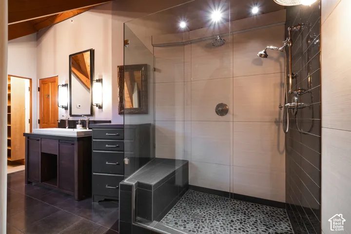 Walk-in shower featuring a pebble-stone floor, integrated bench, glass surround, and dual shower heads