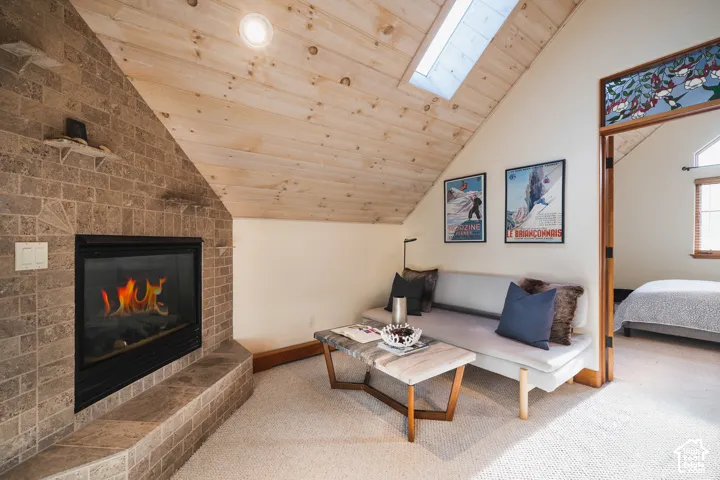 Vaulted wood-paneled ceiling with an integrated skylight and a full-height stone-finish fireplace