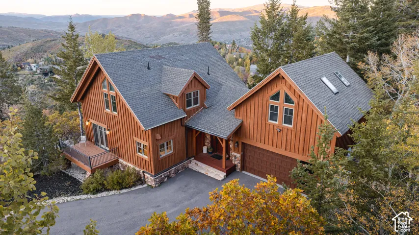 Vertical board-and-batten siding with stone masonry foundation, steep-pitched roofline, multi-pane windows, and attached garage