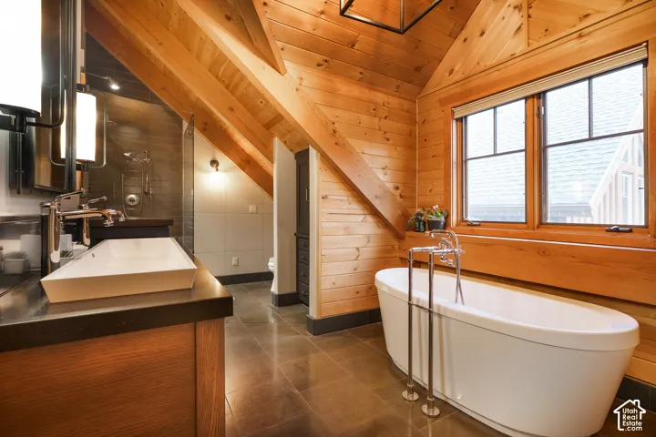 Vaulted tongue-and-groove wood ceiling, freestanding soaking tub with floor-mounted faucet, custom wood vanity with rectangular vessel sink, and slate-finish tile flooring