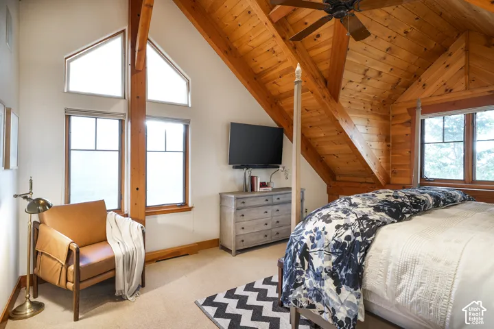 Vaulted ceiling featuring exposed wood beams and wood-plank paneling, complemented by large multi-pane windows and a central ceiling fan