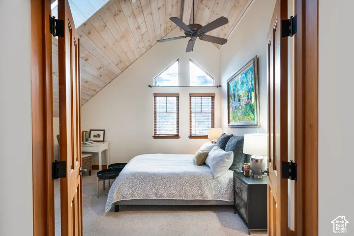 Vaulted ceiling with natural wood-plank finish, triangular gable windows, ceiling fan, and wooden double-door entry