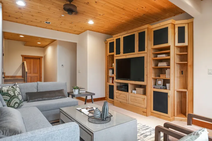 Natural wood plank ceiling, custom built-in cabinetry, recessed lighting, and a solid wood interior door
