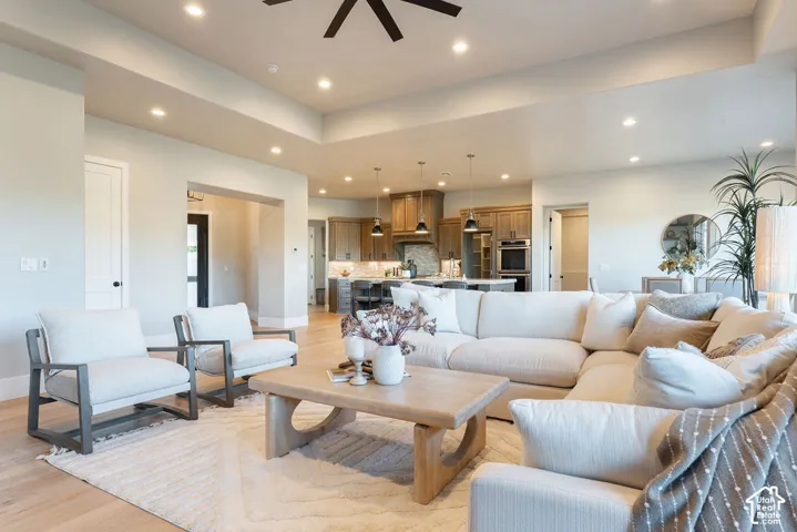 Tray ceiling with recessed lighting, wood-finish flooring, and kitchen featuring built-in cabinetry, an expansive island, and pendant lighting