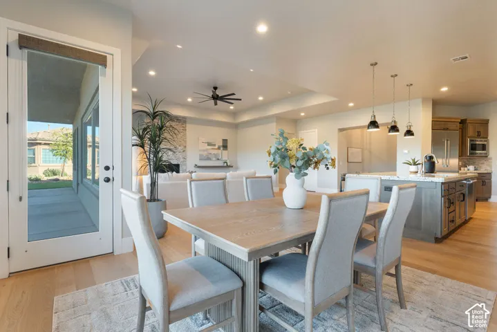 Open-concept kitchen and dining area featuring wood-finish flooring, a central island with stone countertop, recessed lighting, and pendant illumination