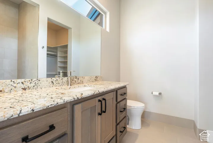 Spa-inspired bathroom featuring a wood-finish vanity with ample storage, quartz countertop with decorative aggregate finish, and modern chrome hardware
