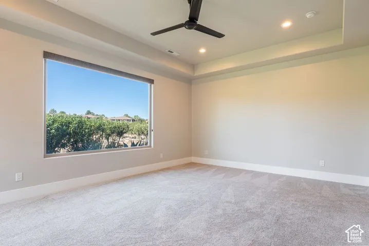 Expansive window with roller shade, recessed lighting, ceiling fan, and tray ceiling detail