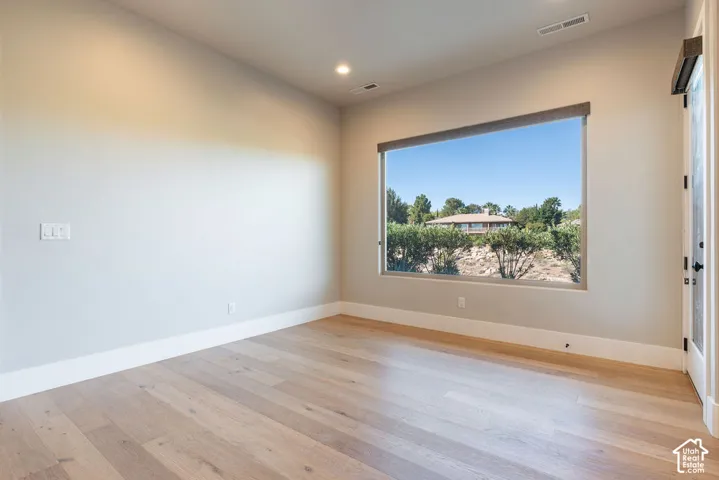 Bright, naturally lit room featuring hardwood flooring, recessed ceiling lighting, and a large picture window framing scenic landscape views