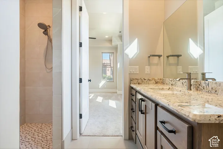 Spa-inspired primary bathroom featuring dual vanities with warm-toned stone countertops, oil-rubbed bronze hardware, and large framed mirrors with integrated lighting