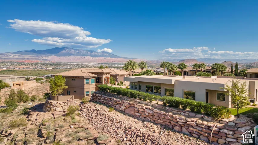 Expansive desert landscaping with rock retaining walls, mature shrubs, and a flat roofline