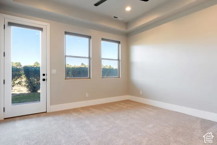 Tray ceiling with recessed lighting, ceiling fan, and light-toned carpet flooring