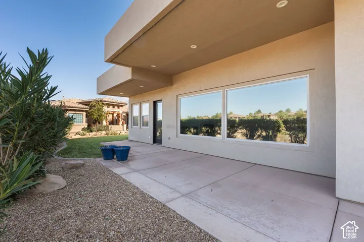 Expansive concrete patio with recessed lighting, large windows, and an adjacent landscaped area featuring gravel and manicured shrubs