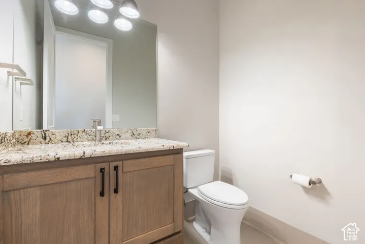 Contemporary bathroom vanity featuring a wood-finish cabinet with dual hardware pulls, speckled stone countertop, and integrated sink
