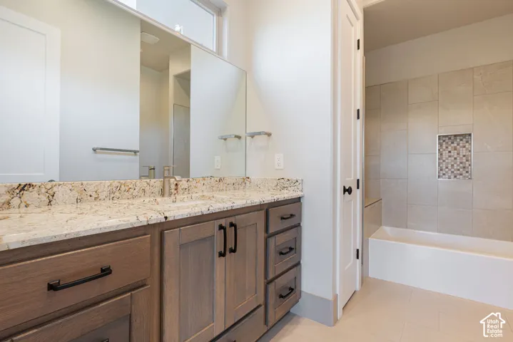 Spa-inspired primary bathroom featuring a wood-finish vanity with dual sinks, granite countertop, and brushed nickel hardware