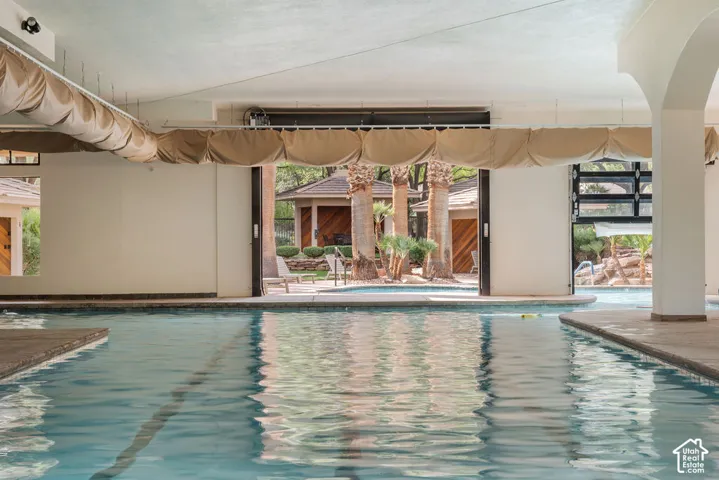 Indoor swimming pool with concrete decking, arched architectural column, and exterior access