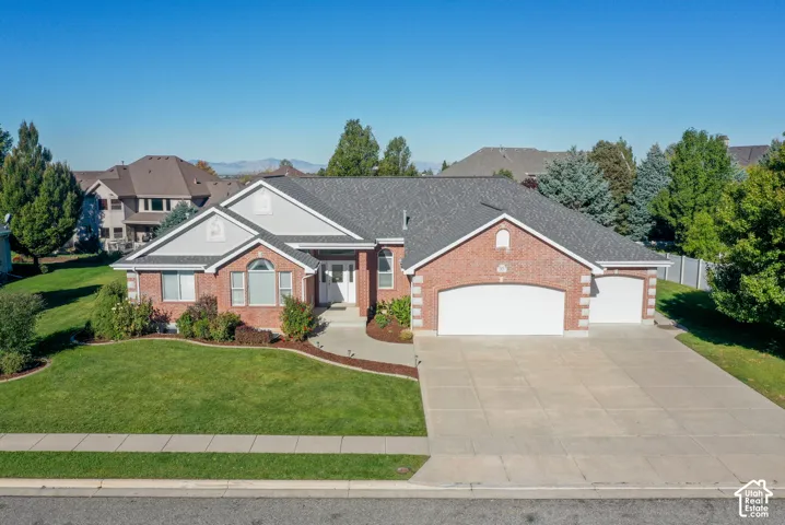 Single-story brick exterior featuring a multi-gabled roofline, concrete driveway, three-car garage, and arched architectural detailing