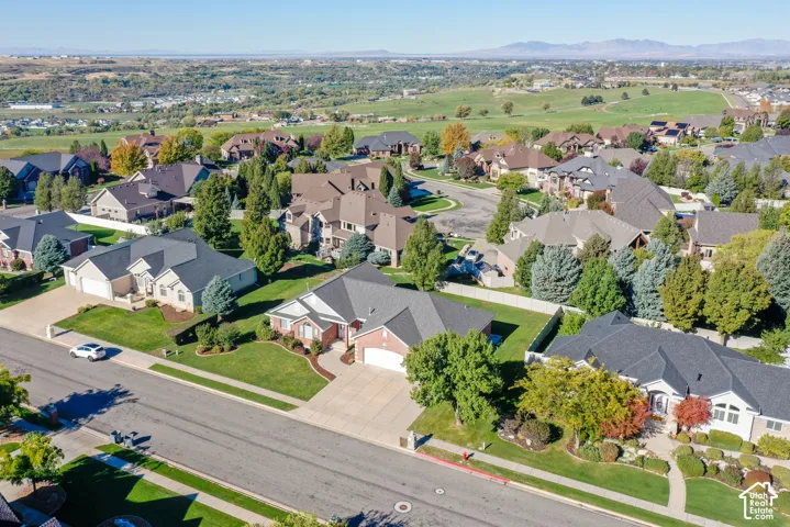Aerial perspective of a suburban neighborhood featuring brick and siding residential exteriors, pitched roofs, concrete driveways, and manicured landscaping