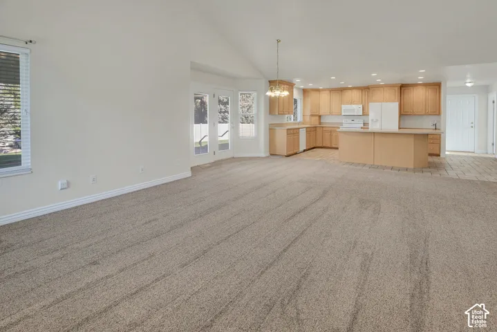 Vaulted ceiling, kitchen featuring wood-finish cabinetry, central island with extended counter, recessed lighting, and dual glass-panel exterior doors