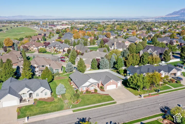 Aerial perspective of residential properties featuring brick and siding exteriors, multi-gabled rooflines, paved driveways, and manicured landscaping