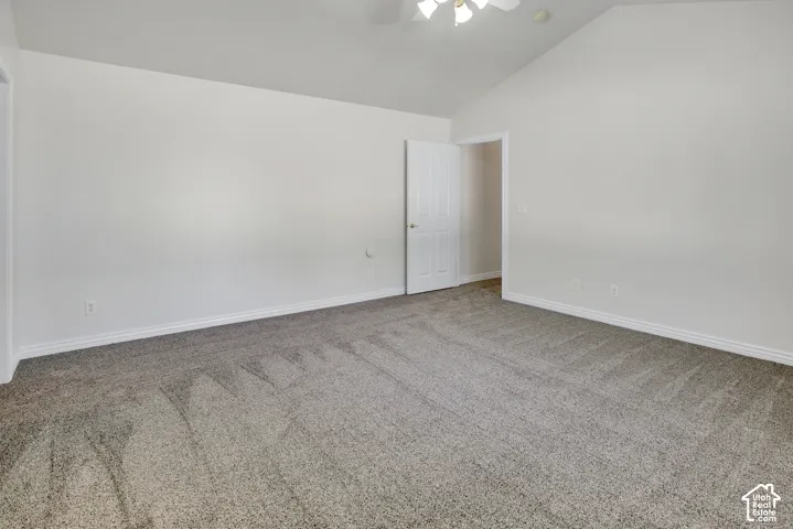 Spacious room with vaulted ceilings, neutral wall tones, wall-to-wall carpeting, and a flush-mount light fixture