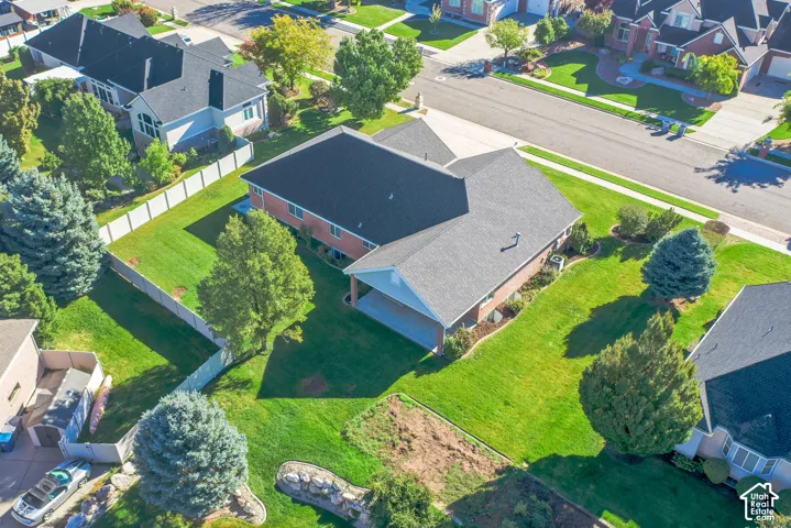 Brick-exterior residence featuring an expansive lawn, a covered rear patio, mature trees, and a white privacy fence