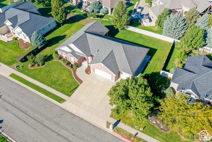 Aerial perspective of a brick and siding exterior featuring a multi-gabled roof, a paved driveway, and an expansive lawn with mature trees and perimeter fencing