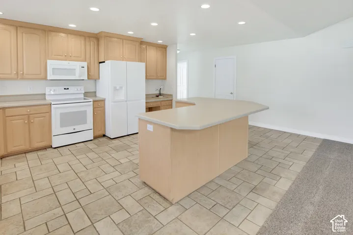 Kitchen featuring light-finish cabinetry, a peninsular island with a solid-surface countertop, tile flooring, recessed lighting, and a suite of white appliances