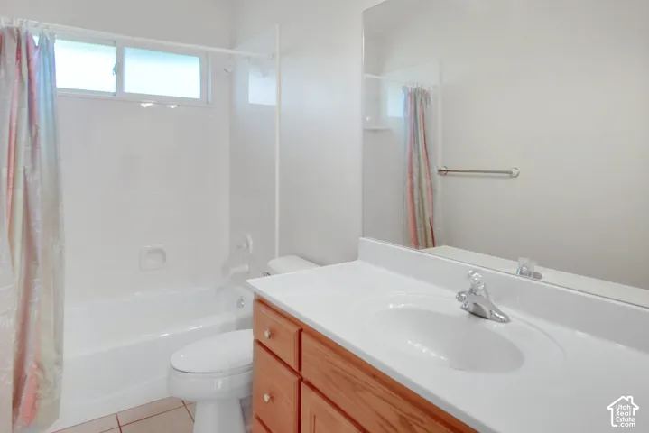 Bathroom featuring a vanity with a white countertop and integrated sink, full-width wall mirror, wood-finish cabinetry, and a tub-shower combination with a sliding window