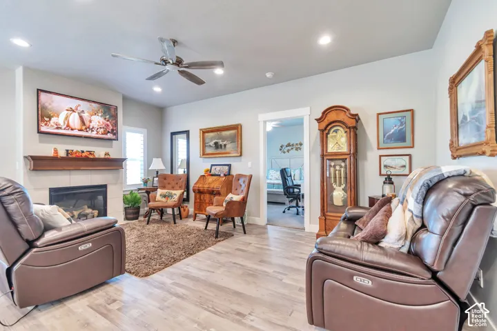 Living area featuring wood-finish flooring, a fireplace with a mantel, recessed lighting, and a ceiling fan