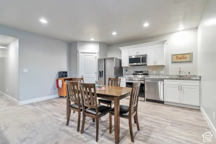 Kitchen featuring white shaker-style cabinetry, stone-finish countertops, stainless steel appliances, recessed lighting, and wood-finish flooring