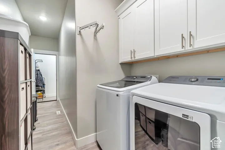 Laundry area featuring white shaker-style wall cabinetry, wood-finish flooring, and a wall-mounted folding drying rack