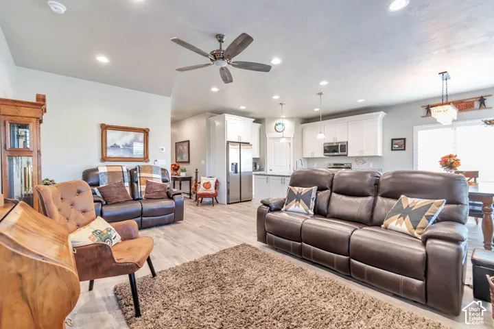 Open-concept living space featuring wood-finish flooring, recessed lighting, a ceiling fan, and white cabinetry