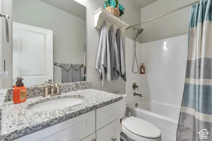 Bathroom featuring a vanity with stone-finish countertop, undermount sink, brushed nickel faucet hardware, and a combination tub and shower enclosure