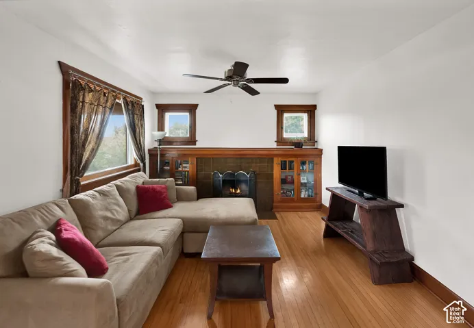 Living area featuring wood-finish flooring, a tile-surround fireplace, and built-in wood cabinetry with glass-front displays