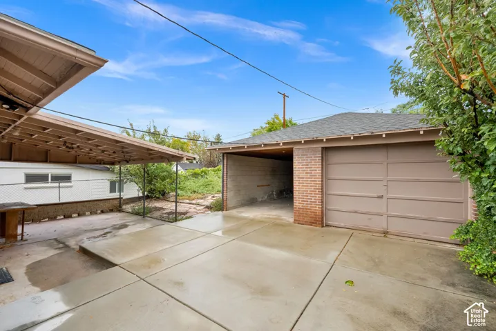 Detached garage with brick masonry accents, concrete driveway, and covered patio space
