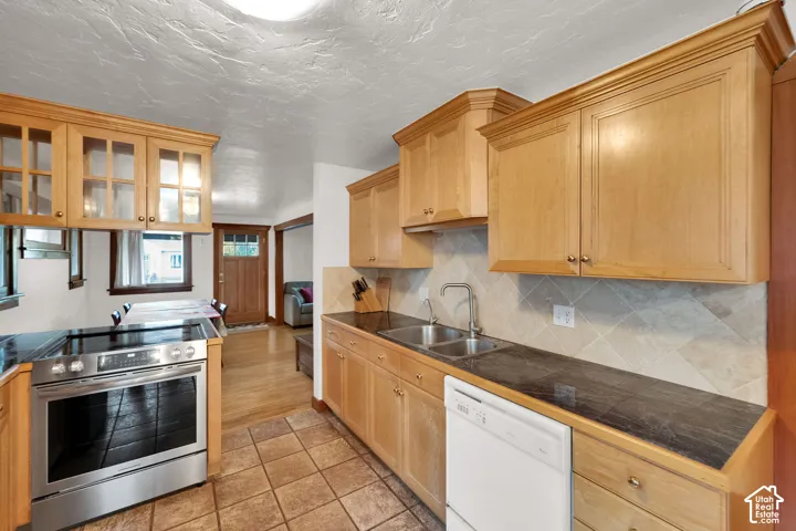 Kitchen featuring natural wood cabinetry, dark stone countertops, diagonal tile backsplash, stainless steel range, and tile flooring