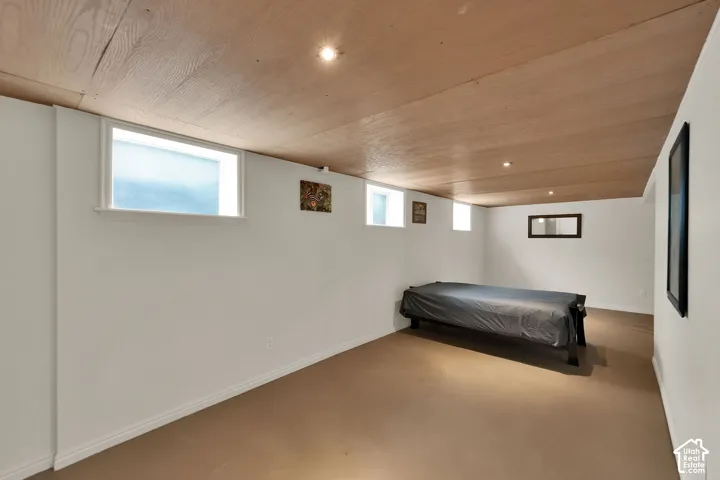 Finished room featuring wood-paneled ceiling, recessed lighting, neutral wall finishes, and multiple egress-style windows