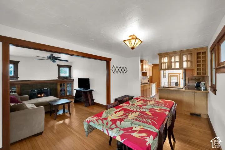 Wood-finish flooring, natural wood trim, fireplace with tile surround, built-in cabinetry, and ceiling-mounted light fixtures