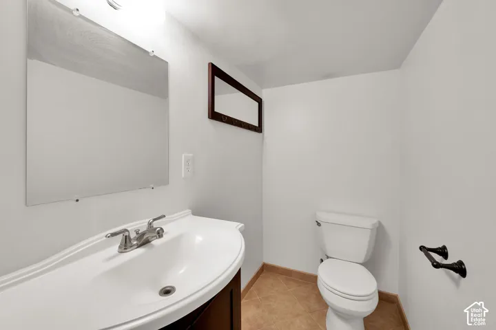 Vanity featuring a white integrated sink, chrome dual-handle faucet, and dark-finish cabinet, complemented by a wall-mounted mirror, ceramic tile flooring, and oil-rubbed bronze hardware