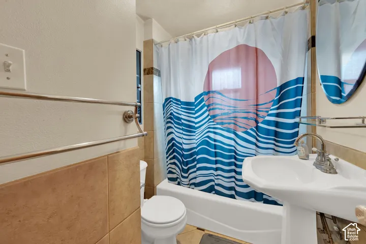 Bathroom featuring a pedestal sink, metallic wall-mounted towel bar, and neutral-toned wall tile