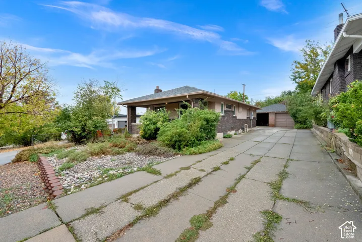 Single-story residence featuring a brick and stucco exterior, covered front porch, concrete driveway, and detached garage